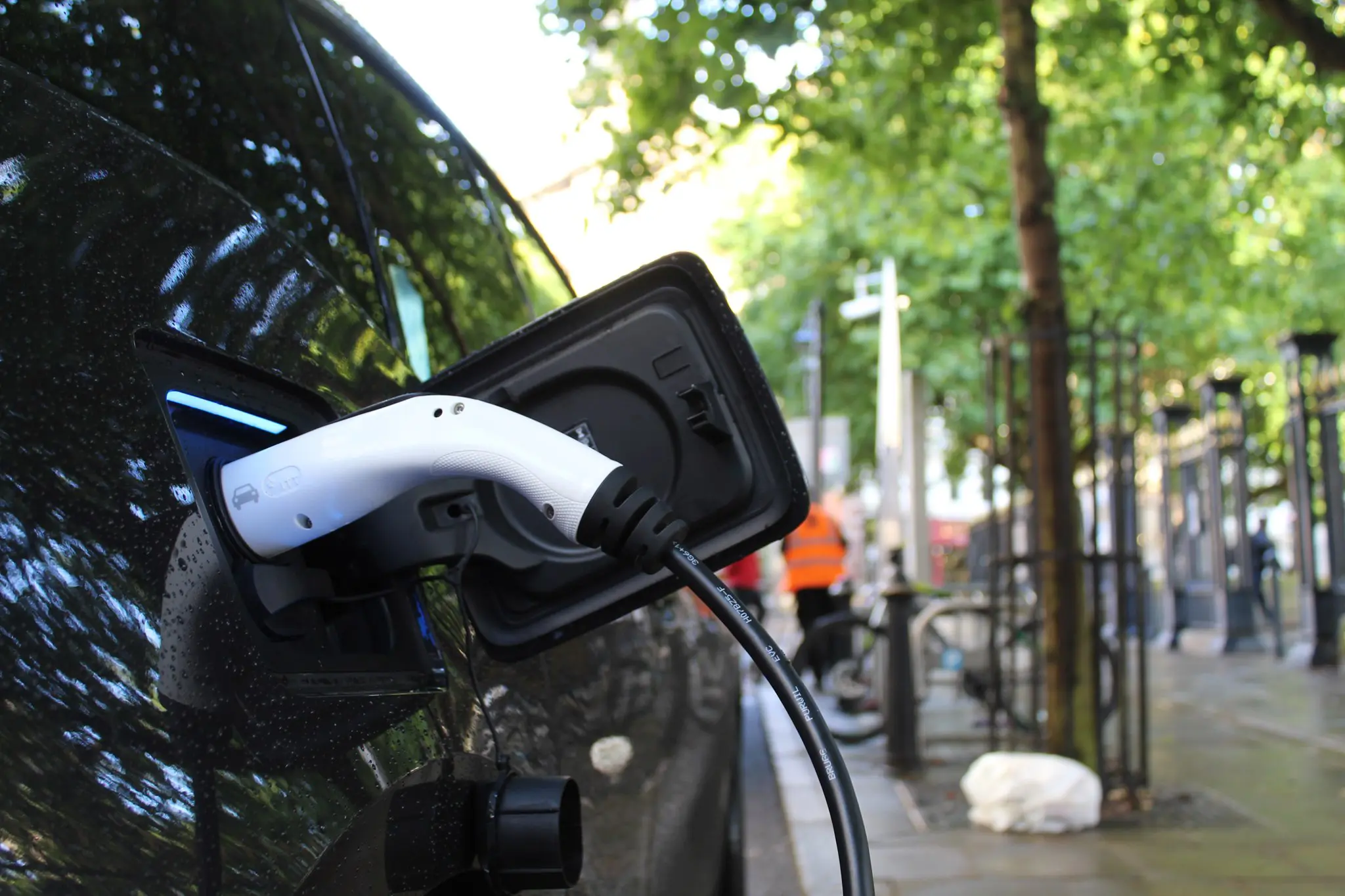 Professional stock photo: EV driver plugging in at urban charging station - Clean energy concept for marketing materials