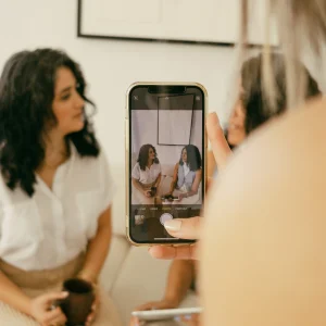 Two women from Fierce Team are sitting and having a conversation, while one person is taking a photo of them on their mobile