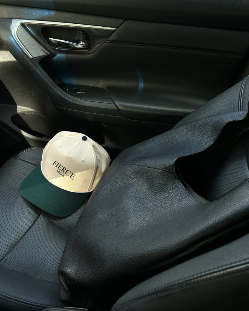 Car interior with a Fierce Media hat resting on the passenger seat, illustrating a calm, trust-focused car buying environment
