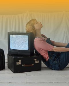 Editorial fashion photography of a woman leaning against a vintage TV with static, representing the evolution of media and the high-concept world of Super Bowl 60 advertising.
