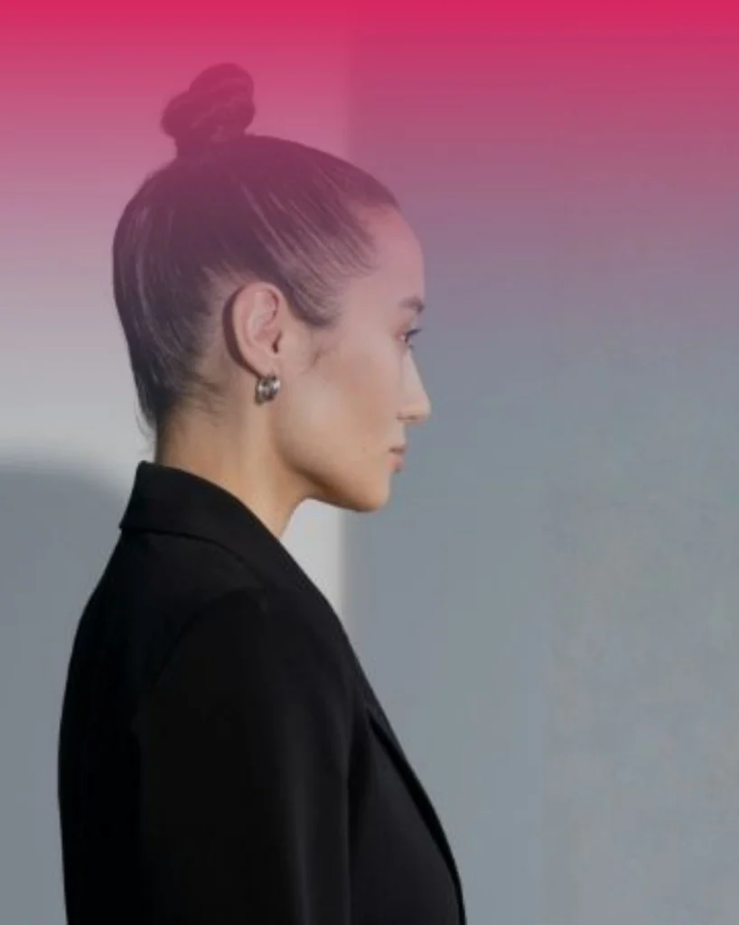 A professional wellness business owner in Canada, with hair in a clean top knot and wearing a black blazer, standing in profile. This image illustrates the "Founder/Team Voice" content pillar for local wellness marketing strategy in 2026.